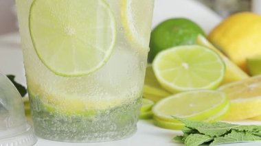 Ev yapımı mojito veya limonata. İçkiyi yakından karıştır. Hafif bir mutfakta serinletici bir içeceği olan plastik bir bardak. Evde alkolsüz mojito yap.