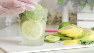 Ev yapımı mojito veya limonata. İçkiyi yakından karıştır. Hafif bir mutfakta serinletici bir içeceği olan plastik bir bardak. Evde alkolsüz mojito yap.