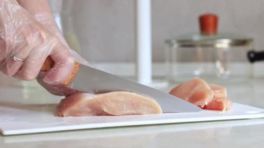 Keskin bir bıçakla taze çiğ tavuk eti kes. Tavuk filetosu yakın plan. Eti dilimlere ayır. Taze çiğ tavuk fileto doğrayan bir kadın kesme tahtasına yakın duruyor.