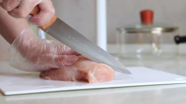 Keskin bir bıçakla taze çiğ tavuk eti kes. Tavuk filetosu yakın plan. Eti dilimlere ayır. Taze çiğ tavuk fileto doğrayan bir kadın kesme tahtasına yakın duruyor.