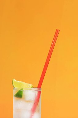 Turuncu arka planda buzlu ve limonlu buzlu çay. Soğuk içecekle yaz kokteyli. Boşluğu kopyala