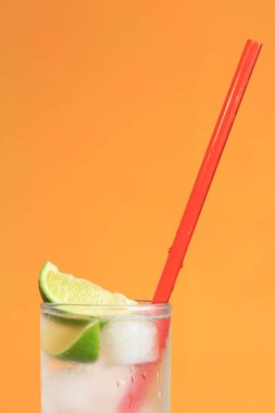 Turuncu arka planda buzlu ve limonlu buzlu çay. Soğuk içecekle yaz kokteyli. Boşluğu kopyala