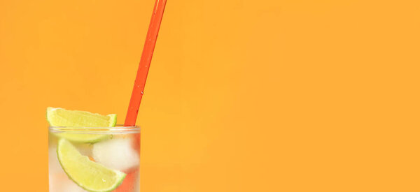 Холодный чай со льдом и лаймом на оранжевом фоне. Летний коктейль с холодным напитком. Копирование пространства