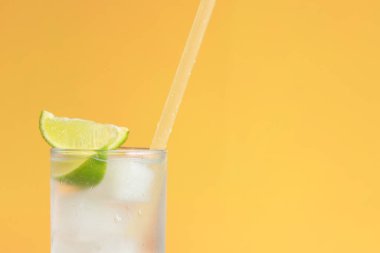 Parlak turuncu arka planda buzlu ve limonlu limonata. Soğuk içecekle yaz kokteyli. Uzayı kopyala Kamışla yakın plan iç.