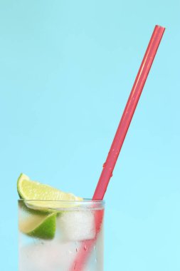 Açık mavi arka planda buzlu ve limonlu limonata. Soğuk içecekle yaz kokteyli. kopyalama alanı. Kamışla yakın plan iç.