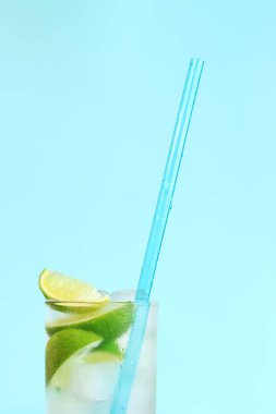 Açık mavi arka planda buzlu ve limonlu limonata. Soğuk içecekle yaz kokteyli. kopyalama alanı. Kamışla yakın plan iç.