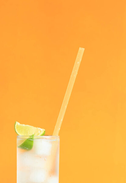 Лимонад со льдом и лаймом на ярко-оранжевом фоне. Летний коктейль с холодным напитком. Принято. Пейте с соломинкой крупным планом