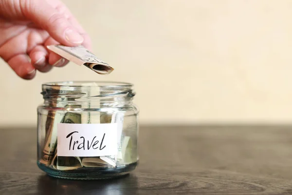 stock image Piggy bank with dollars for travel. Accumulation of financial concept. Glass jar with money. The woman puts more money in the piggy bank