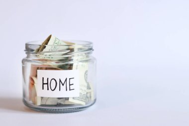 Para dolu cam kavanoz, beyaz arka planda yakın plan. Konut, ev ya da ev ihtiyaçları için dolarları olan domuz kumbarası. Gelecek için para biriktir