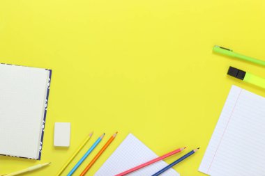 Okula dönelim. Çalışma alanı, üst manzara, düz yatak. Not defterlerini, kalemleri, kalemleri, kalemleri ve sarı arkaplandaki silgiyi aç. Çalışmak ve çalışmak için aksesuarlar. Kırtasiye