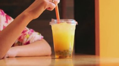 Köpüklü çay. Plastik bardakta bir kızın ellerinde bir içki. Köpüklü çayı pipetle karıştır. Tayvan köpüğü çayı içen kadın.