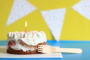 Doğum günü mumlu şenlikli pasta. Çatallı kek. Doğum günü bayraklarıyla şenlikli bir arka planda pasta. Mutlu yıllar.