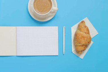 Boş sayfalı not defterini aç, üstten bak. Metin eklemeye hazır. Mavi arka planda ayçöreği olan defter ve kahve. İş planı ve tasarım fikirleri için yukarıdan kompozisyon, samimi ve lezzetli bir kahvaltı.
