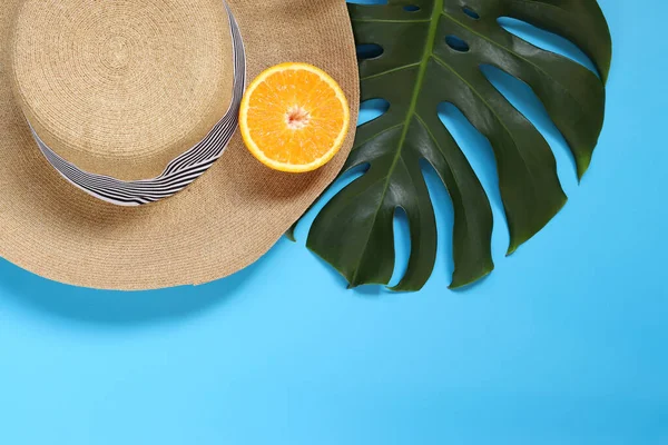 stock image Summer women's hat, monstera leaf and orange on a blue background, empty space for text. Summer concept, copyspace