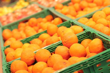 Süpermarkette portakal satışı. Plastik kutularda citrus meyveleri, seçici odaklı yakın çekim. Portakallar mağazanın yan görünümünde. Olgun, sulu, parlak portakal meyvesi. C vitamini ile zenginleştirilmiş meyve.