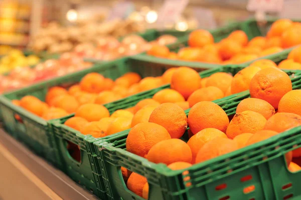 Süpermarkette portakal satışı. Plastik kutularda citrus meyveleri, seçici odaklı yakın çekim. Portakallar mağazanın yan görünümünde. Olgun, sulu, parlak portakal meyvesi. C vitamini ile zenginleştirilmiş meyve.