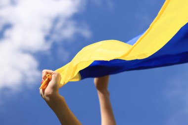 Gökyüzüne karşı Ukrayna bayrağı taşıyan kadın elleri. Kavram: Ukrayna 'da özgürlük için savaş, ülkenin bağımsızlığı. Ukrayna bayrağı rüzgarda dalgalanıyor. Sarı-mavi bayrak