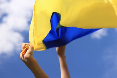 Gökyüzüne karşı Ukrayna bayrağı taşıyan kadın elleri. Ukrayna bayrağı rüzgarda dalgalanıyor. Ukrayna 'nın Bağımsızlık Günü. Sarı-mavi bayrak