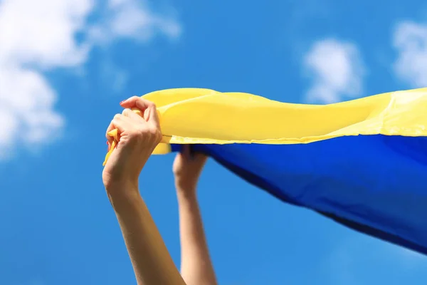 stock image Yellow and blue flag of Ukraine in the woman's hands. Fluttering blue and yellow flag of Ukraine against sky background. Ukrainian flag is a symbol of independence. Celebrate Constitution Independence flag day