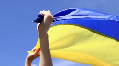 Gökyüzüne karşı Ukrayna bayrağı taşıyan kadın elleri. Ukrayna bayrağı rüzgarda dalgalanıyor. Ukrayna 'nın Bağımsızlık Günü. Sarı-mavi bayrak