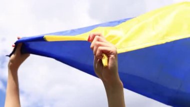 Gökyüzüne karşı Ukrayna bayrağı taşıyan kadın elleri. Ukrayna bayrağı rüzgarda dalgalanıyor. Ukrayna 'nın Bağımsızlık Günü. Sarı-mavi bayrak