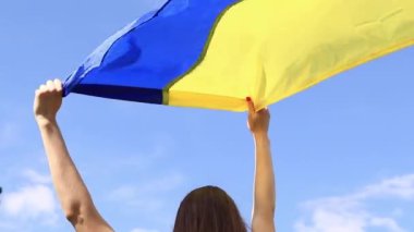 Gökyüzüne karşı Ukrayna bayrağı taşıyan kadın elleri. Ukrayna bayrağı rüzgarda dalgalanıyor. Ukrayna 'nın Bağımsızlık Günü. Sarı-mavi bayrak