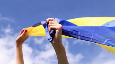Gökyüzüne karşı Ukrayna bayrağı taşıyan kadın elleri. Ukrayna bayrağı rüzgarda dalgalanıyor. Ukrayna 'nın Bağımsızlık Günü. Sarı-mavi bayrak