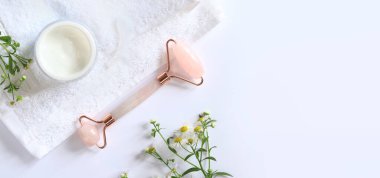 Gül kuvars yüz silindiri. Kozmetik yüz masajı, krem, papatya ve havlu için paten. Düz bir zemin üzerinde yatıyordu. Üst görünüm, alanı kopyala