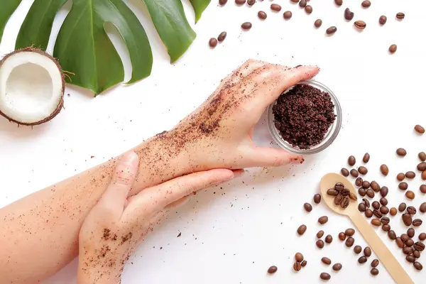 Doğal ev yapımı kahve fırçalı kadın elleri beyaz arka planda, malzemeler yakında, üst tarafta. Spa tedavisi. Spa kişisel bakım konsepti. Düz konum