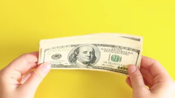 一小叠一百美元的钞票 手里拿着黄色背景的钱 高瞻远瞩 — 图库视频影像