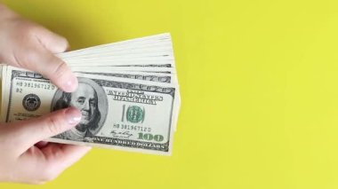 Sarı arka planda 100 dolarlık banknotlar. Piyango kazanmak ya da para kazanmak. Başarılı para yatırımı, ödüller