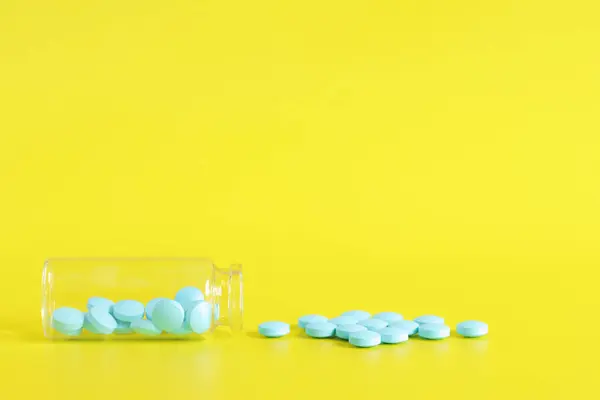 Pillole Blu Vengono Versate Una Bottiglia Vetro Uno Sfondo Giallo — Foto Stock