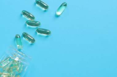 Omega 3. Mavi kauçuk arka planda cam bir şişede kapsüller, üst manzara. Sağlık, tıbbi ilaçlar ve beslenme malzemeleri. Sağlık kavramı