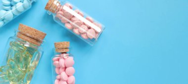 Mavi arka planda cam şişelerde vitaminler, kopyalama alanı. Vitaminler, ağrı kesiciler, sağlık hizmetleri, sağlık hapları ve diyet takviyeleri. B vitamini ve Omega 3