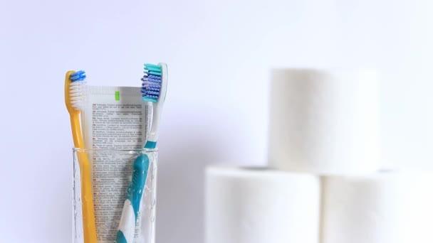 女性の手は歯ブラシを取ります 白い背景にガラスビーカーの歯ブラシ 口腔衛生について 歯のクリーニング 日々の衛生のコンセプト — ストック動画