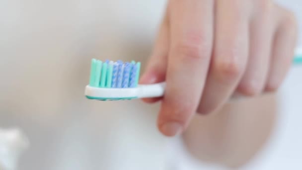 歯ブラシで歯磨き粉を絞る クローズアップ 歯を磨いて 歯科衛生について 浴室の女性がチューブから白い歯磨き粉を絞っている — ストック動画