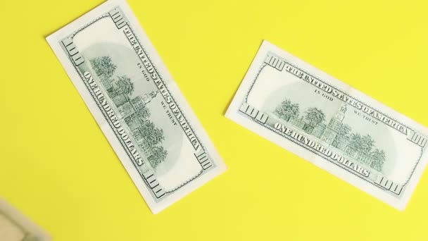 100ドル紙幣の背景 トップビュー 黄色の明るい背景にドルを入れると 順番にお金が表示されます — ストック動画