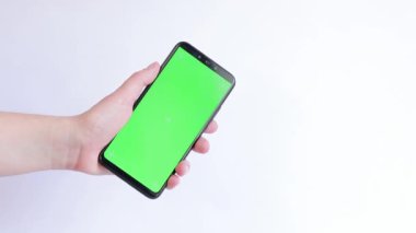 Beyaz arka planda yeşil ekranlı bir telefon. Uygulama veya web sitesi tasarımı için kopya alanı gösteriliyor. Bir kadın elinde açık yeşil ekranlı bir akıllı telefon tutuyor.