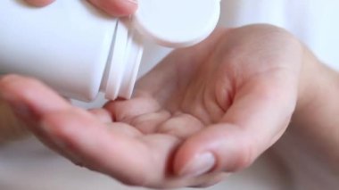 Tabletleri beyaz şişeden eline dök. Vitaminler ve diyet takviyeleri yakın çekim. Günlük vitamin dozları