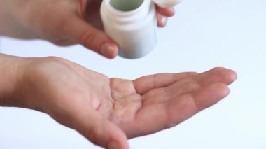 Yeşil tabletleri beyaz şişeden eline dök. Vitaminler ve diyet takviyeleri yakın çekim. Günlük dozda vitamin. İlaç ve uyuşturucu bağımlılığı.