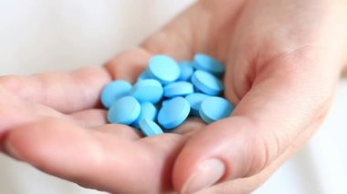 Bir kadının elindeki vitaminler, mavi haplar. Bir avuç dolusu hap al. Sağlık, tıbbi ilaçlar ve besin takviyeleri. İlaç ve uyuşturucu bağımlılığı.