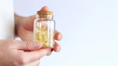 Küçük cam bir şişede Omega-3. Beyaz arka planda parlak sarı şeffaf vitaminler. İlaç ve sağlık hizmetleri. Kadınlarda vitamin ve beslenme takviyeleri