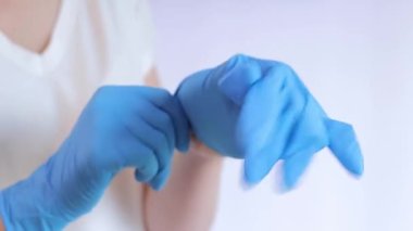 Lateks eldivenli eller. Doktor, hafif arka plan üzerine lastik mavi eldivenler takıyor, yakın plan. Tıp ve sağlık hizmetleri kavramı. Doktor ya da hemşire azot koruyucu eldiven giyiyor.