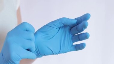Lateks eldivenli eller. Doktor, hafif arka plan üzerine lastik mavi eldivenler takıyor, yakın plan. Tıp ve sağlık hizmetleri kavramı. Doktor ya da hemşire azot koruyucu eldiven giyiyor.