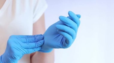 Lateks eldivenli eller. Doktor, hafif arka plan üzerine lastik mavi eldivenler takıyor, yakın plan. Tıp ve sağlık hizmetleri kavramı. Doktor ya da hemşire azot koruyucu eldiven giyiyor.
