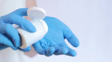 Vitaminleri avucunun içine dök. Lateks eldivenli eller bir kavanoz hap tutuyor. Tıp ve sağlık hizmetleri kavramı, farmakoloji