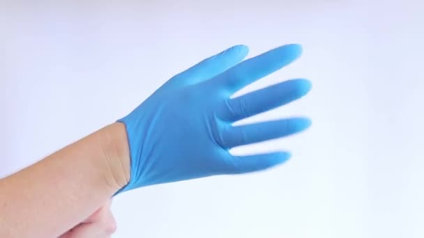 手在乳胶医用手套 医生把橡胶蓝手套戴在手上 背景浅 医学和医疗保健的概念 医生或护士戴氮肥防护手套 — 图库视频影像