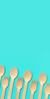 Tek kullanımlık ahşap çatallar ve kaşıklar mavi arka planda, üst manzara. Çevre dostu tek kullanımlık mutfak gereçleri, fotokopi alanı. Düz yatıyordu