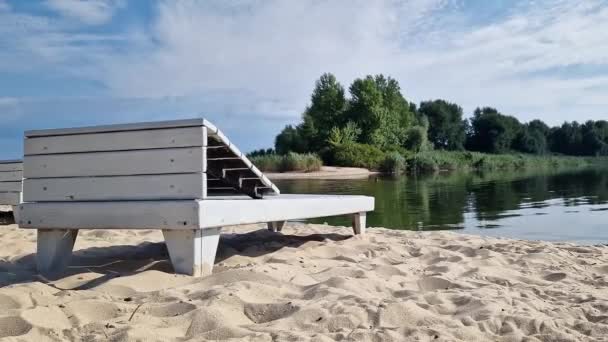 ウクライナのドニーパー川の岸にある木製のデッキチェア 夏のアウトドアレクリエーション 夏のシーズンは 水の近くで休憩してください 美しい風景 サンバース — ストック動画