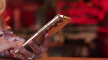 Telefona yakın çekim yapan eller, restoran ya da kafe. Barda akıllı telefonlu bir kadın eli. Gadget. İnternet araması veya çevrimiçi iletişim